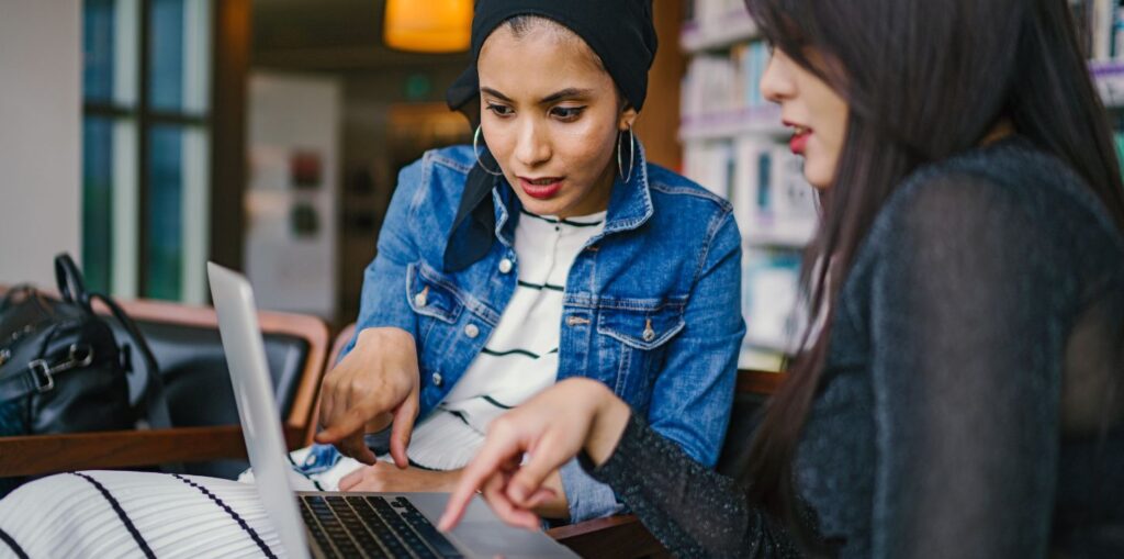 Two woman looking at a laptop screen.