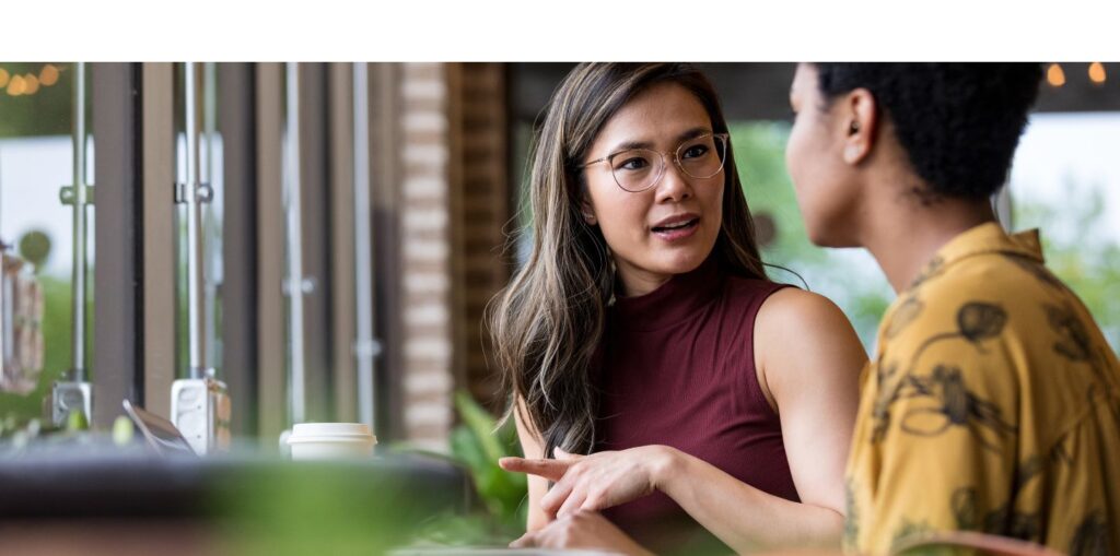 Two women at cafe talking.